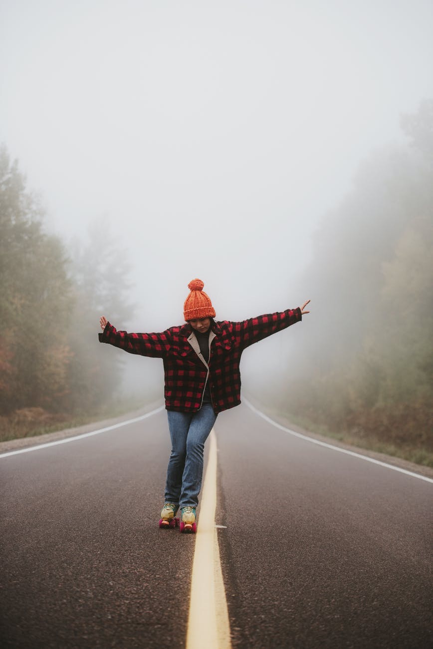 woman standing on empty road with arms stretched out